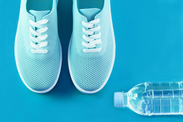 Sneakers bright mint color with a bottle of water on a purple background.