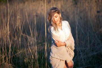 Cute charming girl in summer in the field. Young woman is happy and feels free outdoors