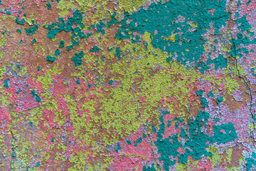 an old painted wall with pealing paint, yellow, blue, pink spots