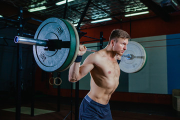 Naklejka na ściany i meble Muscular fitness man preparing to deadlift a barbell over his head in modern fitness center.Functional training.Snatch exercise. Cross style fit, deadlift