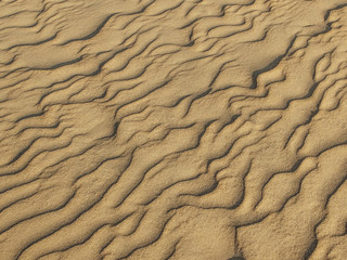 texture of sand waves on the beach or in the desert. the ripples of the sand is diagonal.
