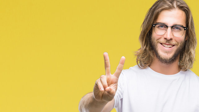 Young handsome man with long hair wearing glasses over isolated background smiling looking to the camera showing fingers doing victory sign. Number two.