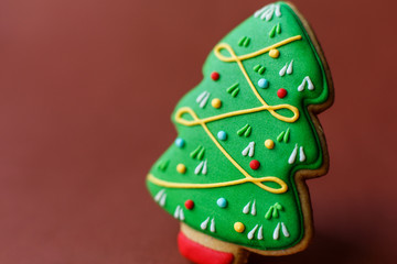 Christmas holiday sweets. Christmas holiday traditions. Christmas tree gingerbread on dark red background.Copy space