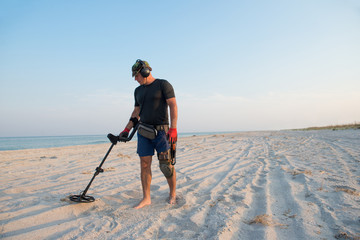 Man with a metal detector on a sea sandy beach