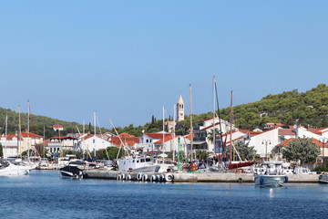 Fototapeta na wymiar Panorama of a yacht marina in the town of Jezera in Croatia in the Dalmatia region. The ships moored in the port of a quiet fishing town in a sunny, clear day. Tourist marine business. Rest by sea