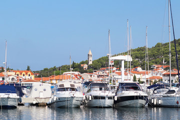 Fototapeta na wymiar Panorama of a yacht marina in the town of Jezera in Croatia in the Dalmatia region. The ships moored in the port of a quiet fishing town in a sunny, clear day. Tourist marine business. Rest by sea