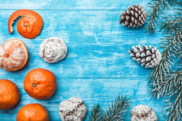 Wallpaper of azure wood, open, sea. Mandarins. Green fir tree. Decorative cones. Space for Xmas and New Year Message. Sweets for holidays. Xmas and Happy New Year composition. Flat lay, top view