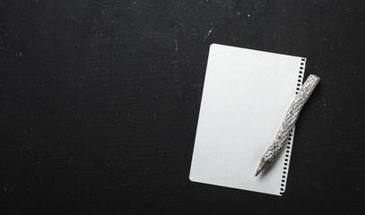 White sheet and pencil wooden on black background. Holiday concept, top view, flat lay, overhead view