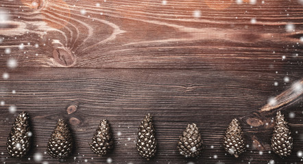 Horizontal brown wood background with golden cones at the bottom. Holiday space for winter, xmas,...