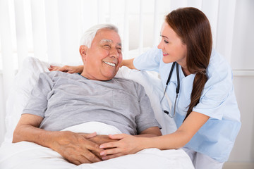 Nurse Looking At Happy Male Patient In Clinic