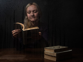 Naturally beautiful millennial woman reading book at rainy autumn day