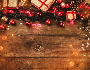 Wooden background, With red lights, toys and gifts arranged at the top, square-shaped, with light bulbs. With congratulatory message space. Top view.