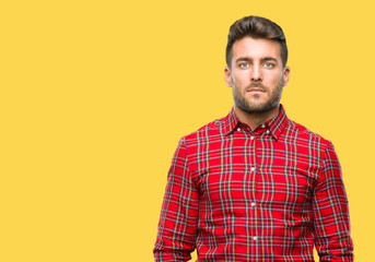 Fototapeta premium Young handsome man over isolated background with serious expression on face. Simple and natural looking at the camera.