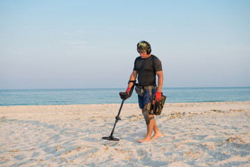 Man with a metal detector on a sea sandy beach