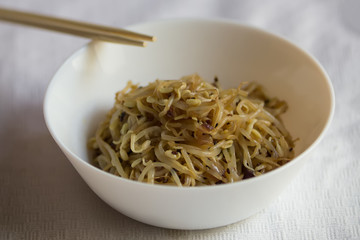 Korean food, soy sprount marinated with garlic and soy sauce with chopstick, selective focus, close up