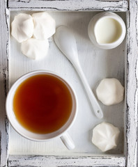 Fototapeta na wymiar A cup of black tea with white mini marshmallow (homemade white zephyr). Copy space