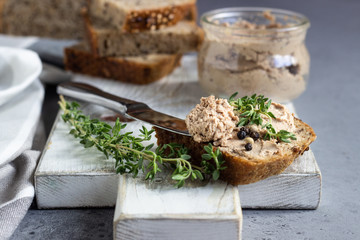 Fresh homemade liver pate in a glass jar and multigrain bread, selective focus. - obrazy, fototapety, plakaty