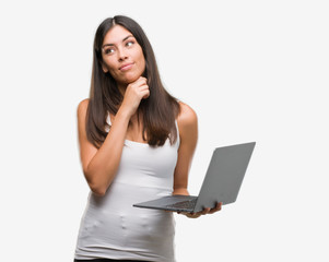 Fototapeta premium Young hispanic woman using computer laptop serious face thinking about question, very confused idea