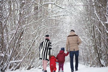 Fototapeta na wymiar Young family with children are walking in the winter park. Winte