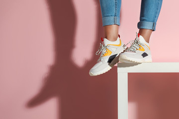 Woman in stylish sneakers near color wall, closeup. Space for text