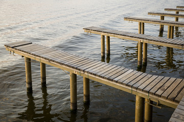Yachts and boat berths with empty spaces. Coastal landscape in background.
