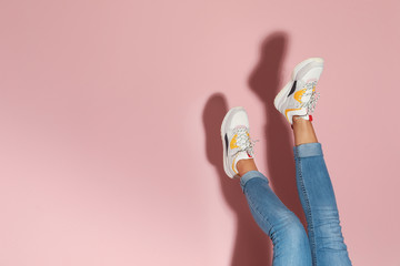 Woman in stylish sneakers near color wall, closeup. Space for text - obrazy, fototapety, plakaty