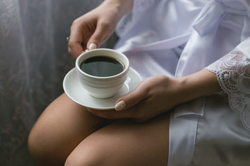 Girl with a cup of coffee on her knees close-up