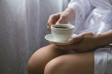 Girl with a cup of coffee on her knees close-up