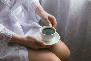 Girl with a cup of coffee on her knees close-up
