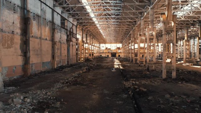 Abandoned and haunted industrial creepy warehouse inside, old ruined grunge factory building, shot from drone flying inside, toned
