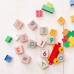 Closeup of wooden cubes with numbers 2019 and multi-color toy bricks on white wooden background. Early learning and development.