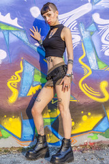 Obraz na płótnie Canvas tattooed rebel girl posing against a wall painted