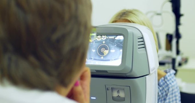 Woman doctor working with the refractometer machine. Close-up of ophthalmology technology
