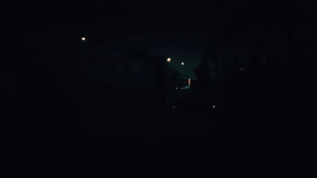 Passenger train passing slowly through the city at night. Outside view from the window.