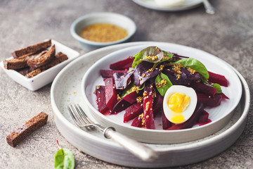 salad from boiled beet, young leaves of spinach and beets with honey-garlic sauce and egg
