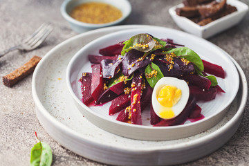 salad from boiled beet, young leaves of spinach and beets with honey-garlic sauce and egg
