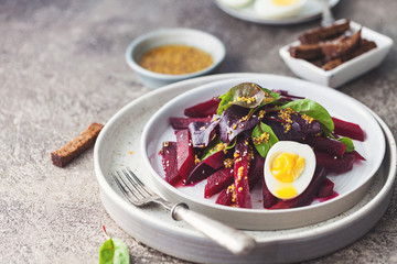 salad from boiled beet, young leaves of spinach and beets with honey-garlic sauce and egg