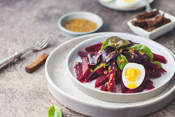 salad from boiled beet, young leaves of spinach and beets with honey-garlic sauce and egg