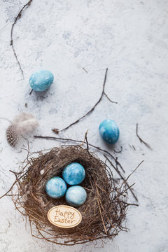 happy easter! decorated quail eggs in a nest on a light background