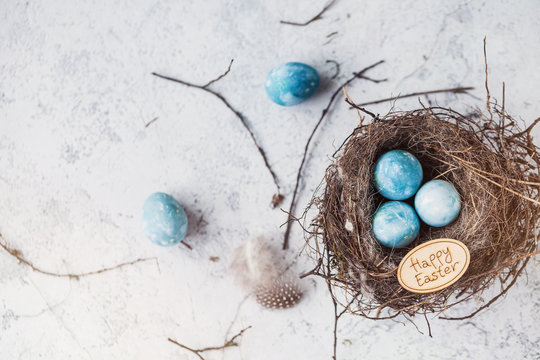 happy easter! decorated quail eggs in a nest on a light background