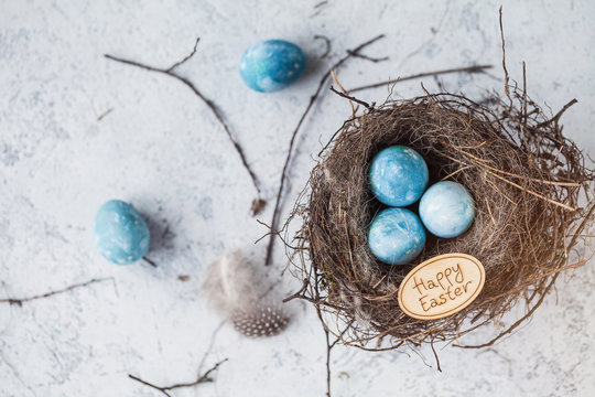 happy easter! decorated quail eggs in a nest on a light background