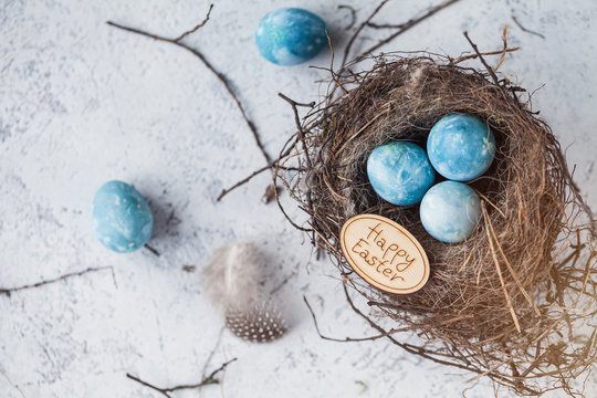 happy easter! decorated quail eggs in a nest on a light background