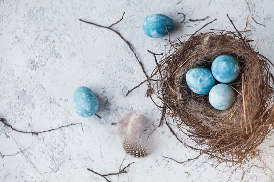 happy easter! decorated quail eggs in a nest on a light background