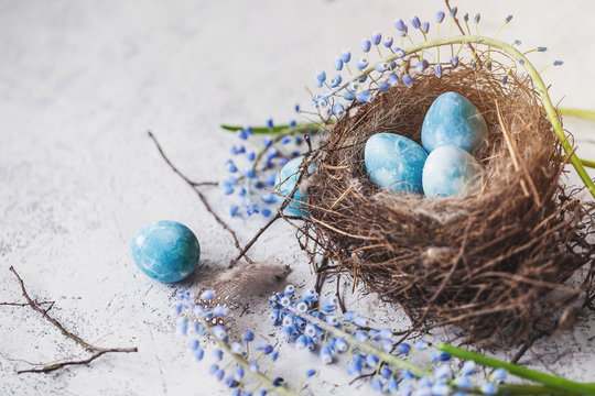 happy easter! decorated quail eggs in a nest on a light background