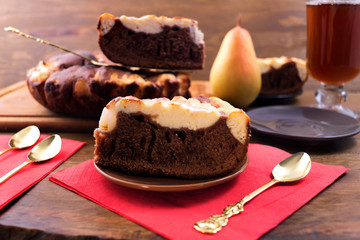 Fototapeta na wymiar Chocolate cake with curd layer and pear, Cutlery for dessert, a glass of tea.