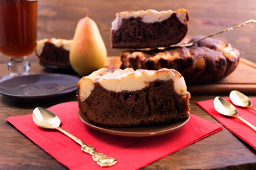 Fototapeta na wymiar Delicious dessert of chocolate cake with cottage cheese and pear, tea in a glass, Cutlery for cake.