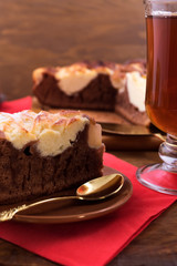 Pie dough with cocoa and a layer of white cottage cheese, laid on a plate with a spoon for dessert, a glass of tea on a wooden background.