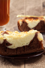 Cut cake with cottage cheese and cocoa, a glass of tea, newspaper background.