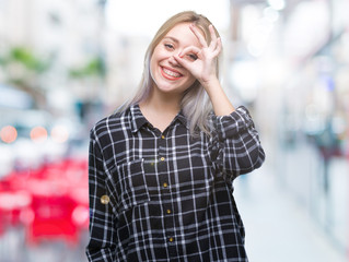 Fototapeta premium Young blonde woman over isolated background doing ok gesture with hand smiling, eye looking through fingers with happy face.
