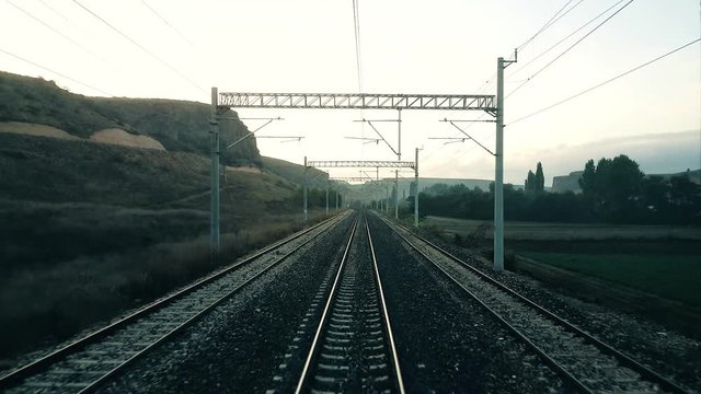 Passenger train slowing down and stops on the railroad in the morning, view from the rear of train 